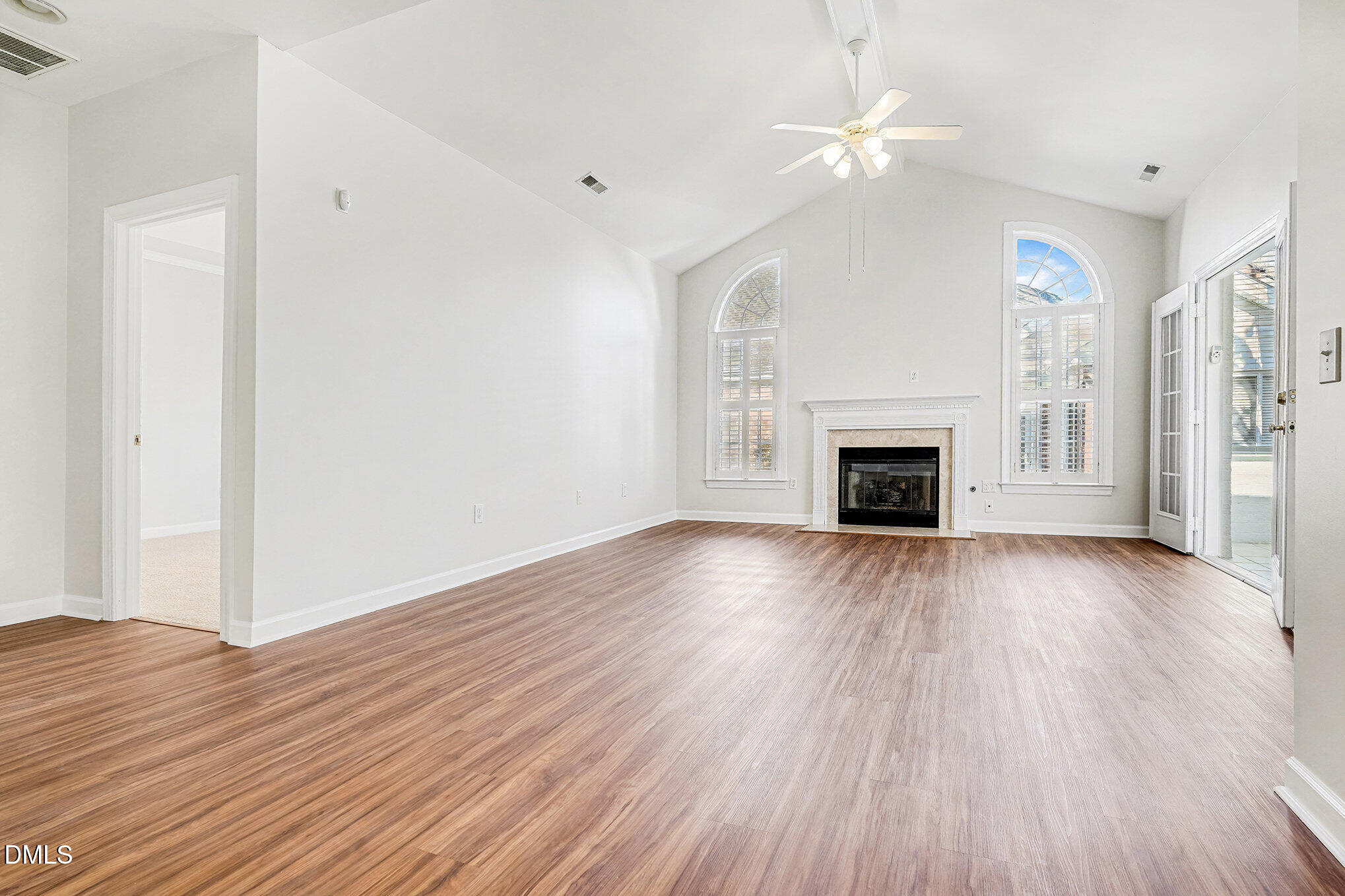 4703 Lewisham Court Raleigh, NC 27612 - Photo 5 of 27 an empty room with wooden floor fireplace and windows
