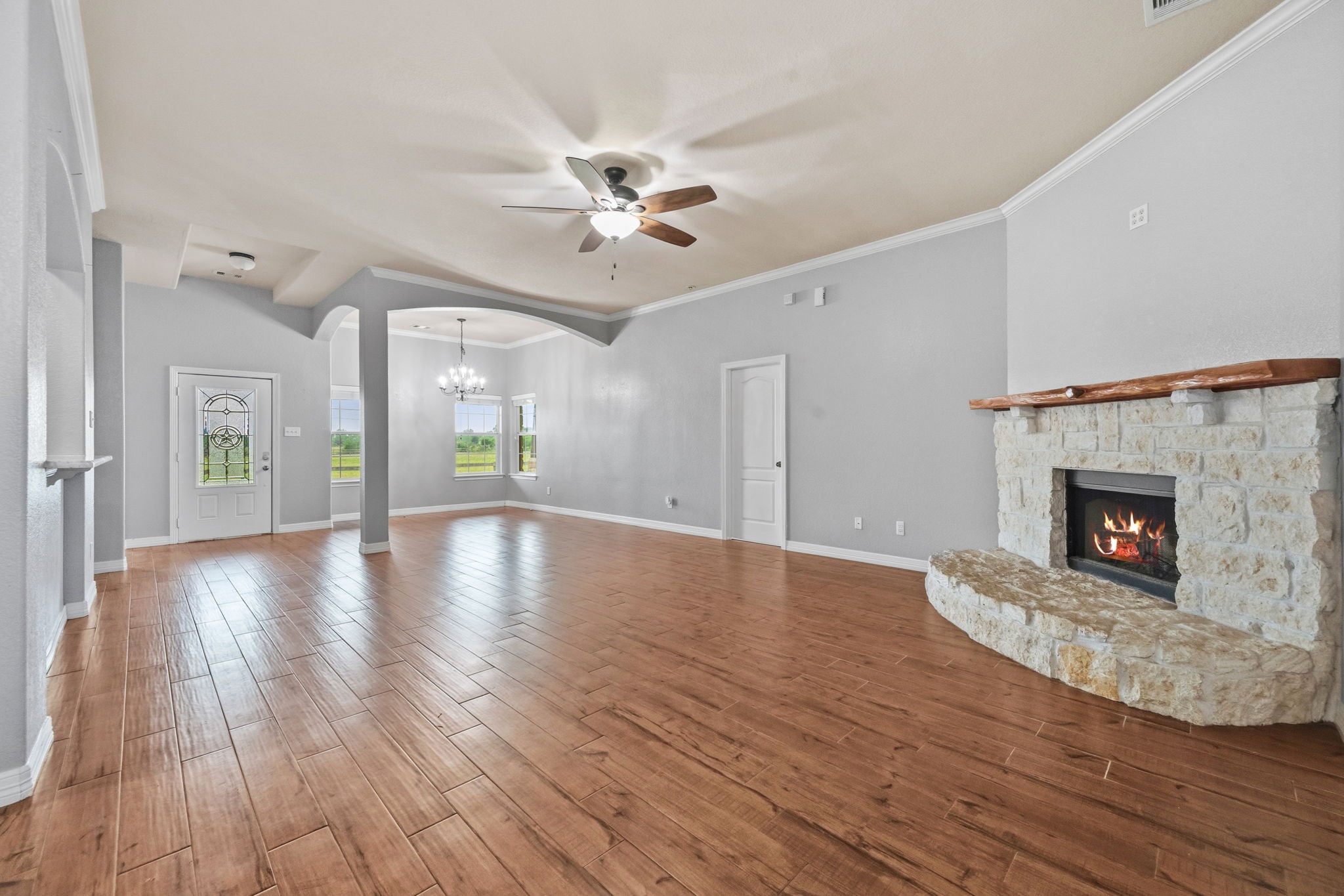 1405 Big Hill Road Winnie, TX 77665 - Photo 22 of 43 a view of a livingroom with wooden floor a ceiling fan a fireplace and windows