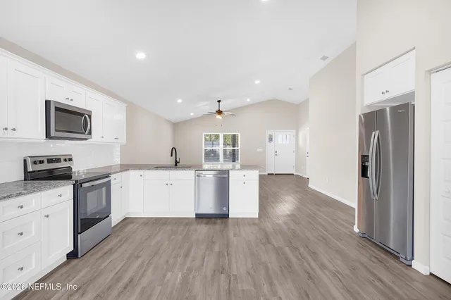 a large kitchen with a wooden floor and stainless steel appliances