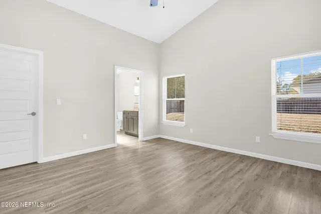 an empty room with wooden floor and windows