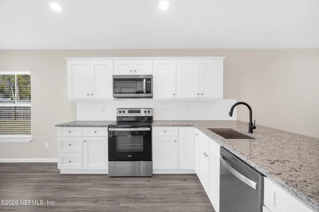 a kitchen with stainless steel appliances granite countertop a stove top oven a sink and dishwasher