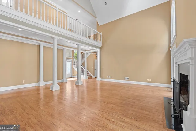 an empty room with wooden floor a fireplace and windows