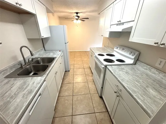 a kitchen with granite countertop a sink a stove and refrigerator
