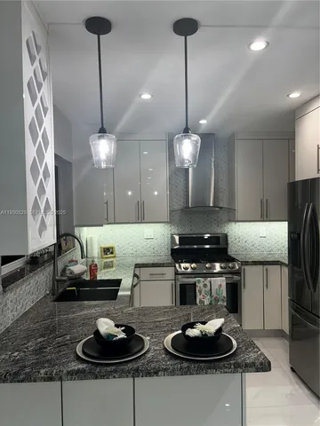a kitchen with granite countertop white cabinets and stainless steel appliances