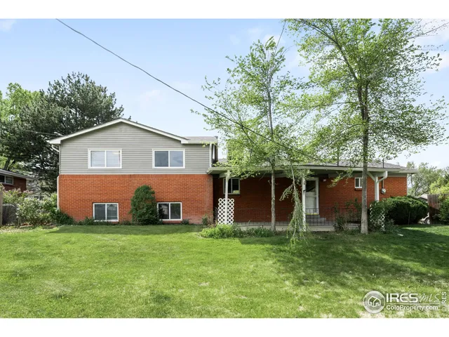 a front view of house with yard and trees in the background