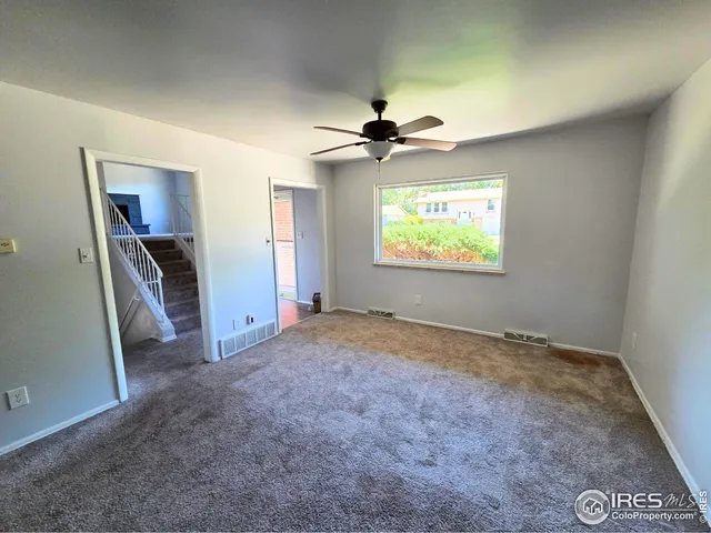 an empty room with windows and a ceiling fan