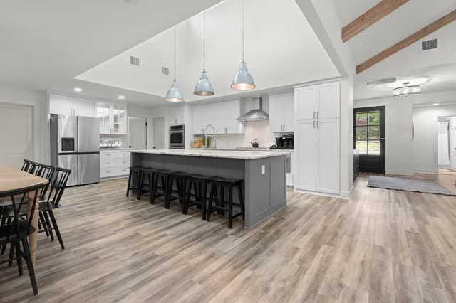 a kitchen with a dining table chairs stainless steel appliances and cabinets