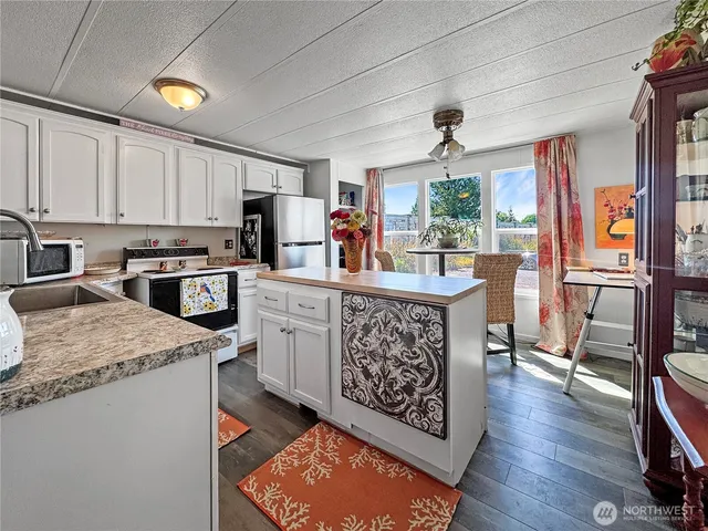 a kitchen with stainless steel appliances granite countertop a stove top oven a refrigerator a dining table and chairs with wooden floor