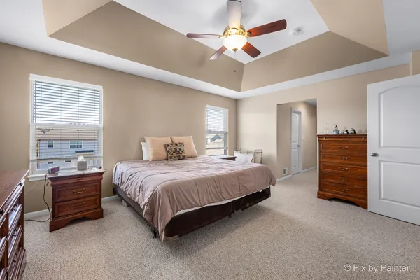 a spacious bedroom with a bed a dresser and a chandelier