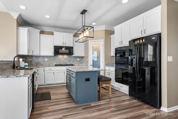 a kitchen with granite countertop a refrigerator stove top oven and sink