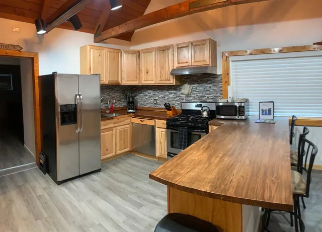 a kitchen with stainless steel appliances granite countertop a stove a sink dishwasher a refrigerator a microwave oven with cabinets and wooden floor