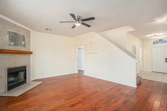 a view of an empty room with wooden floor and a fireplace