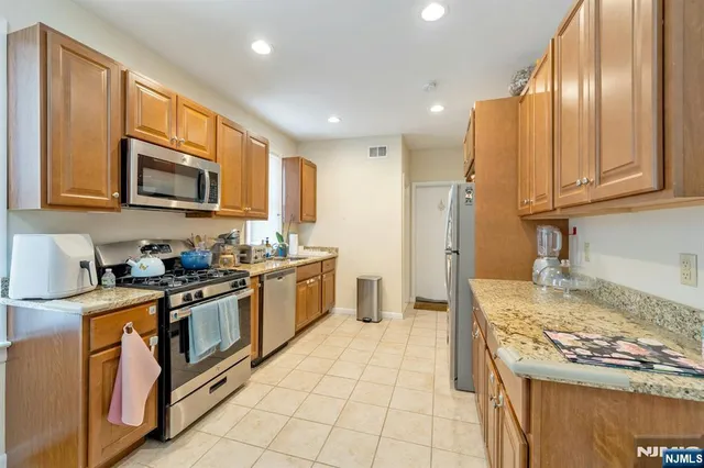 a kitchen with stainless steel appliances granite countertop a stove top oven a sink dishwasher and a refrigerator