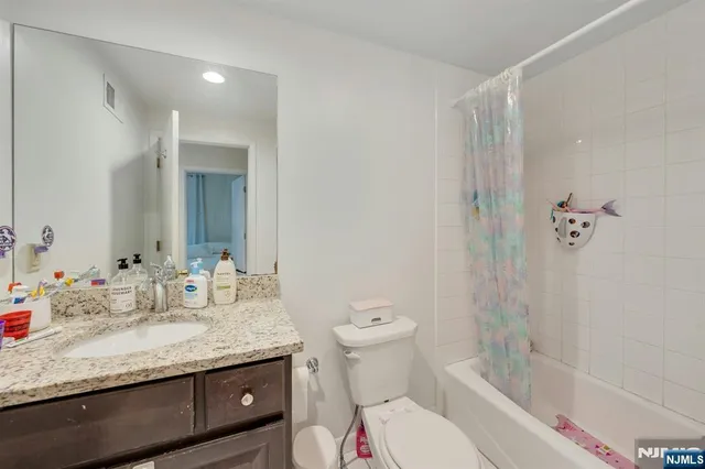 a bathroom with a granite countertop sink a toilet and shower