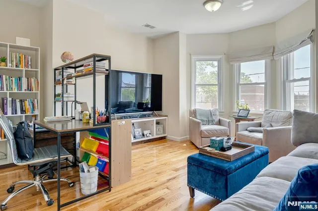 a living room with furniture a flat screen tv and a floor to ceiling window