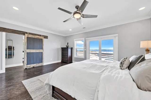 a bedroom with a large bed a flat tv screen and a ceiling fan
