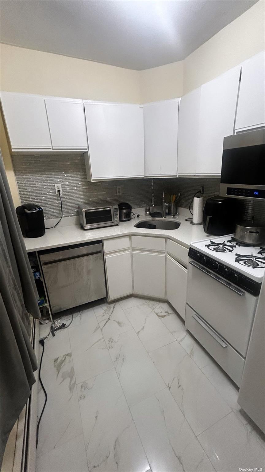 55 Tulip Avenue, Unit 63 Floral Park, NY 11001 - Photo 4 of 7 a kitchen with stainless steel appliances a sink a stove a microwave and cabinets