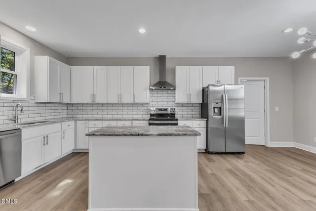 a kitchen with stainless steel appliances granite countertop a refrigerator a stove and a sink