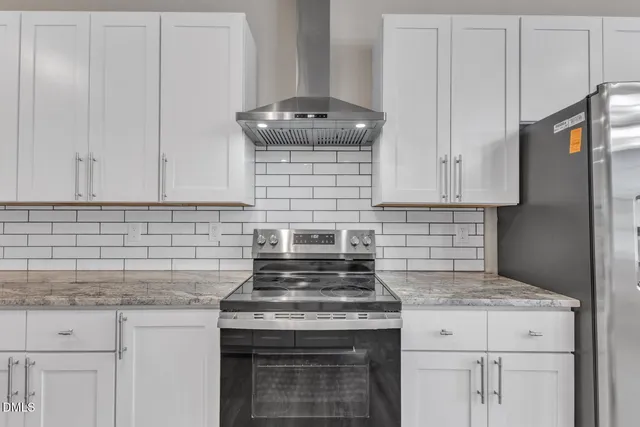 a kitchen with granite countertop white cabinets and a stove
