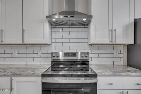 a kitchen with granite countertop a stove and a white cabinets