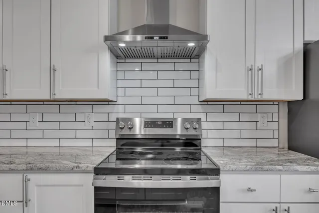a kitchen with granite countertop a stove and a white cabinets