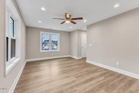 an empty room with wooden floor a ceiling fan and windows