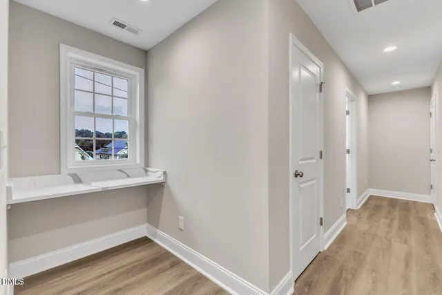 a view of an empty room with wooden floor and a window