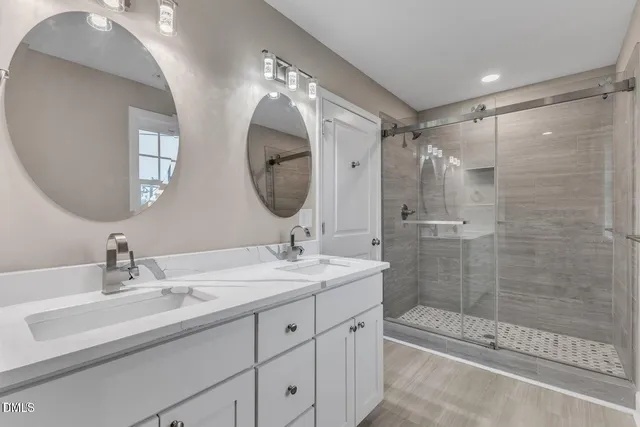 a bathroom with a double vanity sink mirror and shower