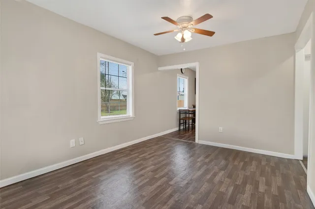 an empty room with wooden floor chandelier fan and windows