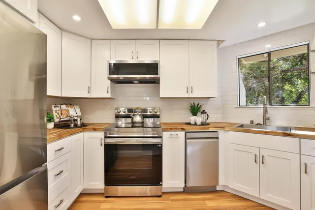 a kitchen with stainless steel appliances granite countertop a stove a sink and white cabinets