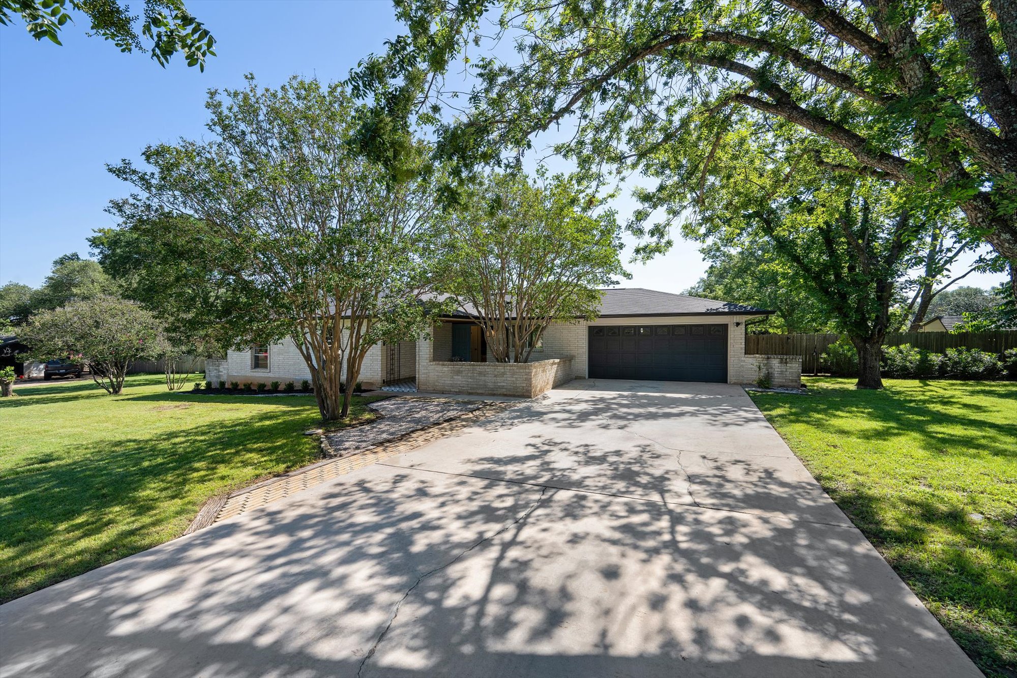 109 Woodland Road Georgetown, TX 78628 - Photo 2 of 40 Mature trees frame a charming home with a paved driveway and well-maintained lawn.