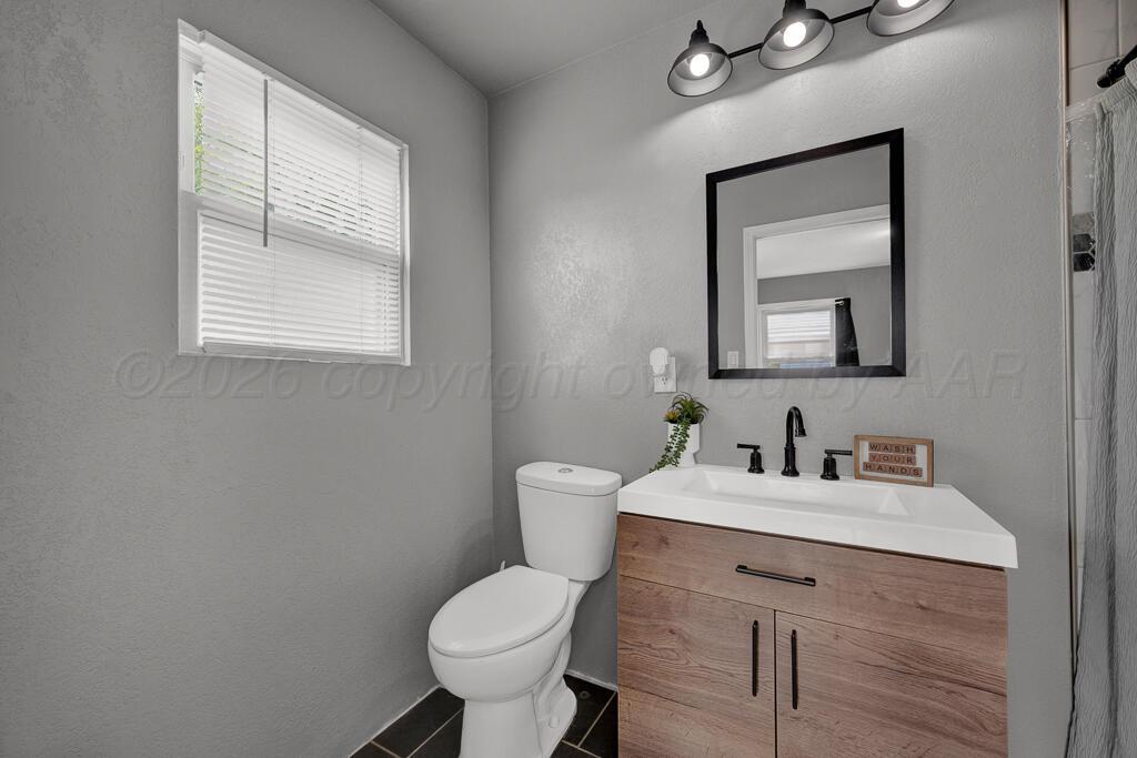 504 East 5th Street Sunray, TX 79086 - Photo 16 of 22 a bathroom with a toilet sink and mirror