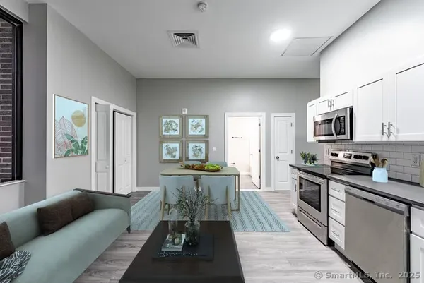 a living room with stainless steel appliances furniture and a kitchen view