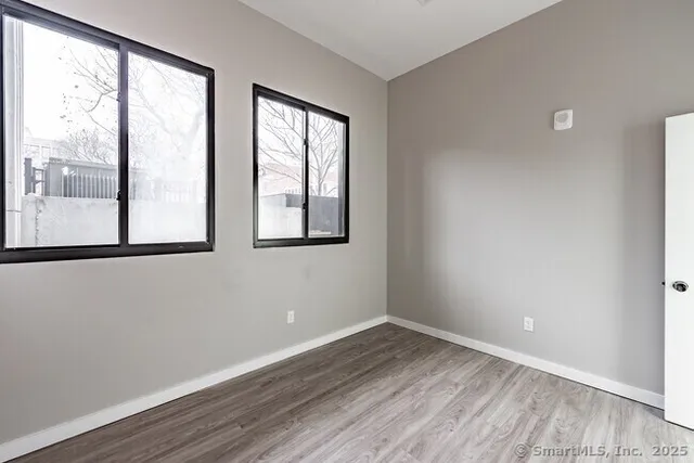 an empty room with wooden floor and windows