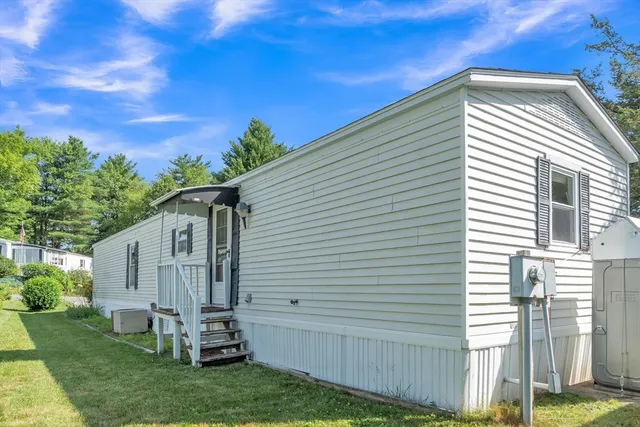 a view of a white house next to a yard and large trees