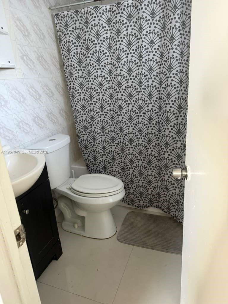 3100 Northwest 91st Street, Unit 3100 Miami, FL 33147 - Photo 5 of 5 a white toilet sitting next to a shower curtain