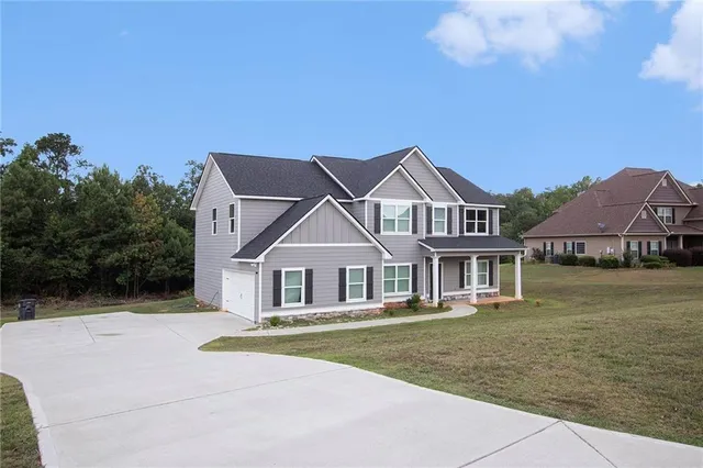a front view of a house with a garden and lake view