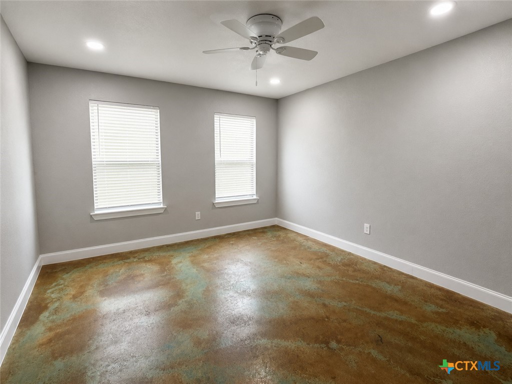 661 West Austin Street, Unit Q Luling, TX 78648 - Photo 6 of 9 an empty room with windows and ceiling fan