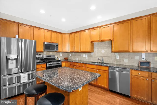 a kitchen with stainless steel appliances granite countertop a stove top oven a sink dishwasher and refrigerator with wooden floor