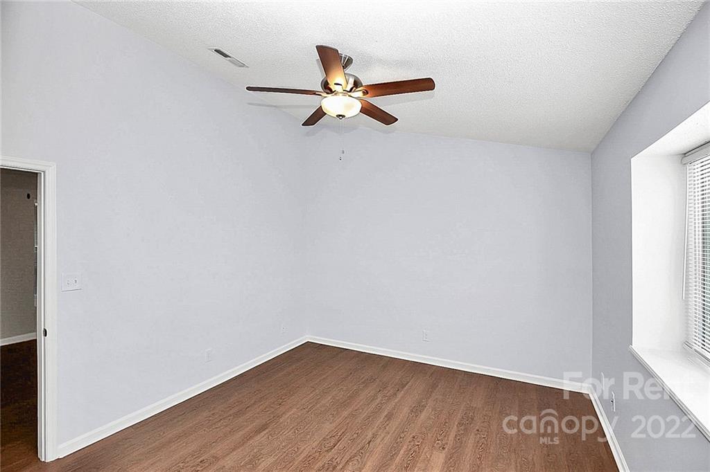 9517 Newell Hickory Grove Road, Unit 4 Charlotte, NC 28215 - Photo 9 of 13 an empty room with wooden floor a ceiling fan and windows
