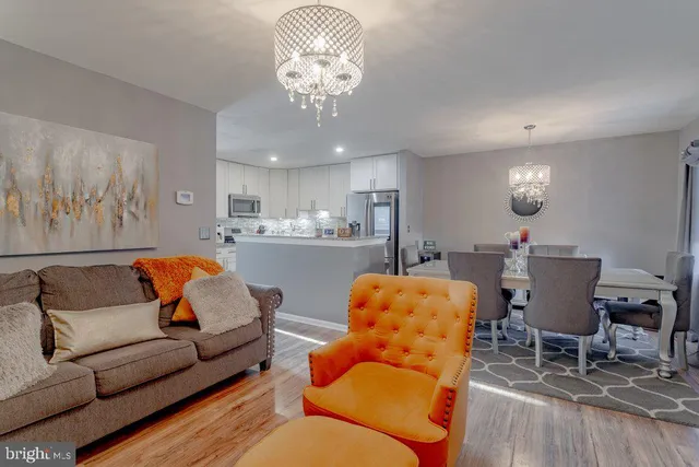 a living room with furniture kitchen view and a chandelier