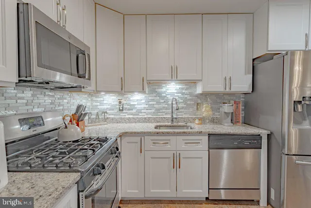 a kitchen with stainless steel appliances granite countertop a stove a refrigerator and a sink