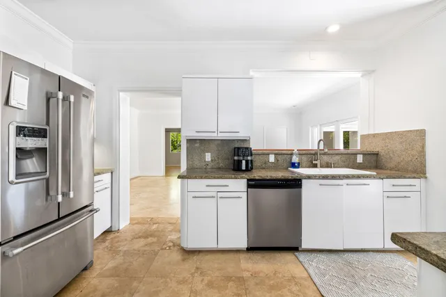 a kitchen with stainless steel appliances granite countertop a refrigerator a stove a sink and white cabinets