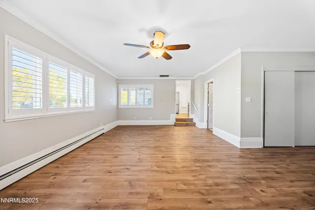 a view of empty room with wooden floor and fan