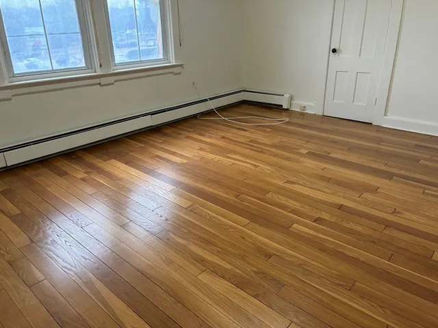 a view of empty room with window and wooden floor