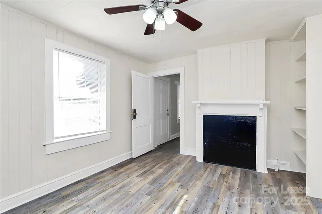 a view of an empty room with a window and fireplace