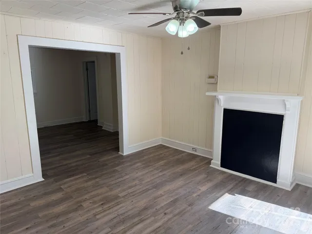 a view of an empty room with wooden floor and a fireplace
