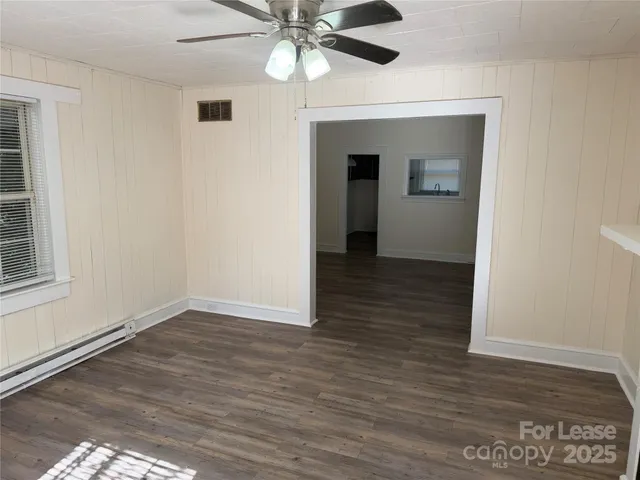 an empty room with wooden floor fan and windows
