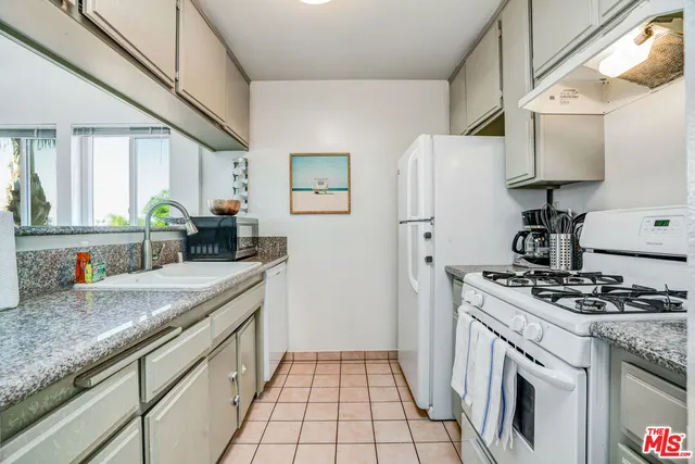 a kitchen with granite countertop a sink stove and refrigerator
