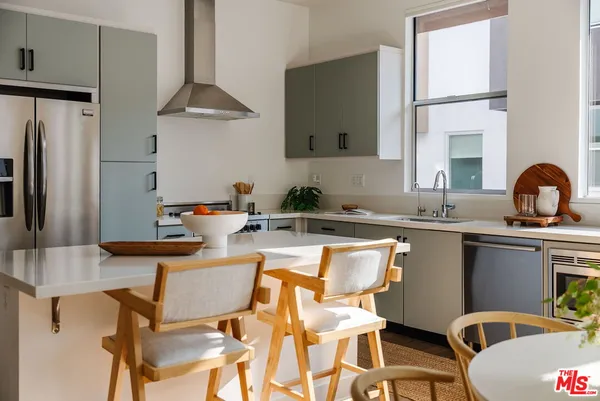 a kitchen with stainless steel appliances granite countertop a sink a stove and chairs